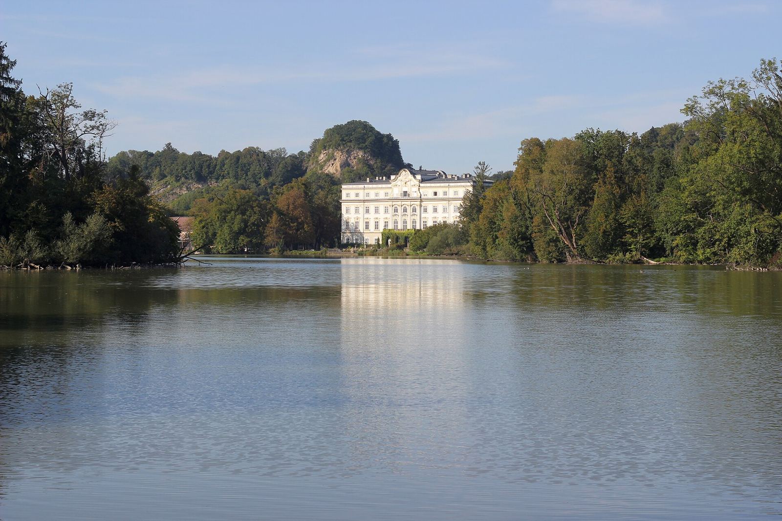 Palacio de Leopoldskron reflejado en su lago con montañas al fondo