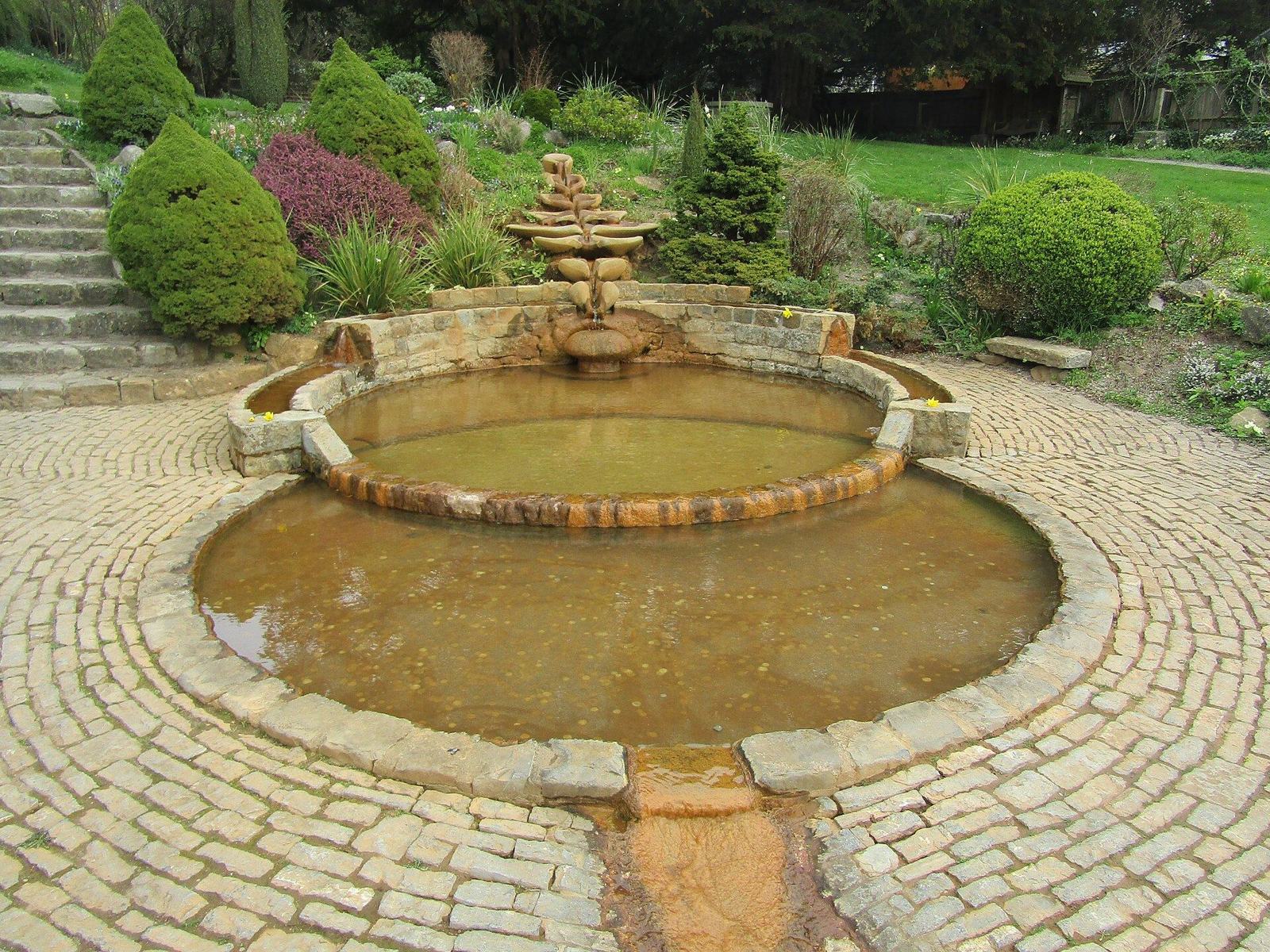 Tapa de hierro forjado del pozo de Chalice Well rodeada de jardines