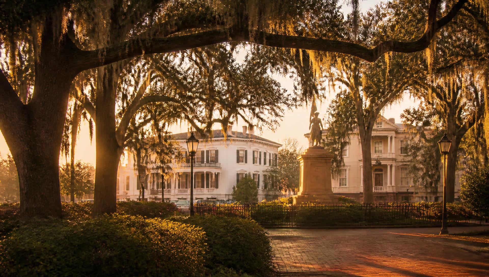 Plaza histórica de Savannah al atardecer con robles centenarios cubiertos de musgo español y mansiones del siglo XIX