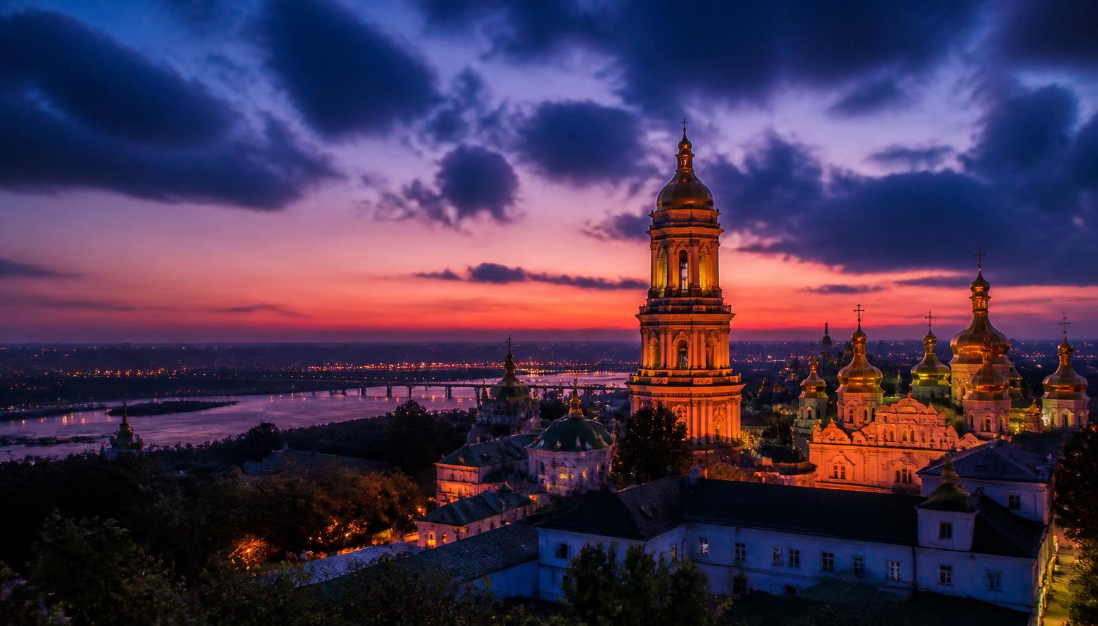 Cúpulas doradas de un monasterio ortodoxo de Kyiv iluminadas al atardecer sobre el río Dniéper